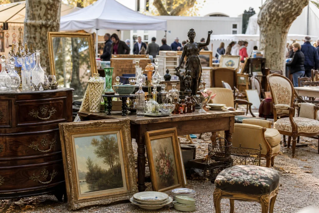 shoppers browsing antique and vintage market stalls at Invaluable in Place Charles David, 30400 Villeneuve-lès-Avignon, France