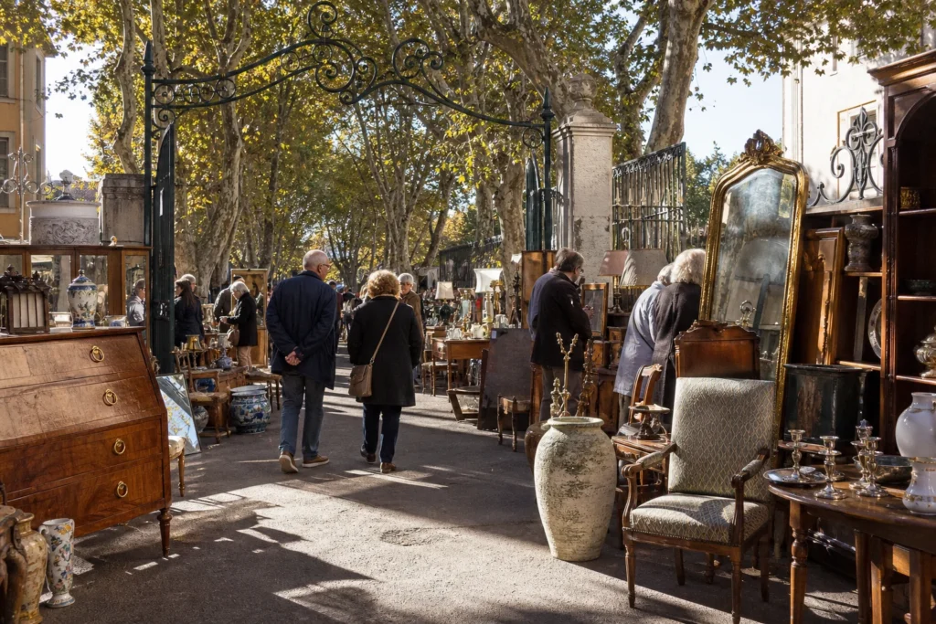 shoppers browsing antique and vintage market stalls at Le Quartier des Antiquaires in France, Provence